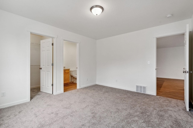 unfurnished bedroom featuring a walk in closet, carpet floors, a closet, and ensuite bathroom