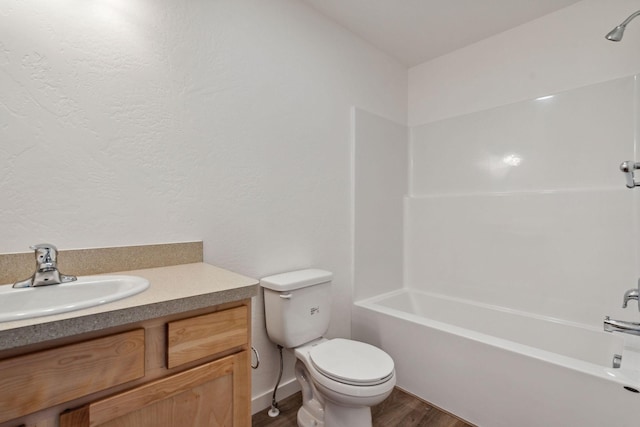 full bathroom with vanity, hardwood / wood-style floors, washtub / shower combination, and toilet