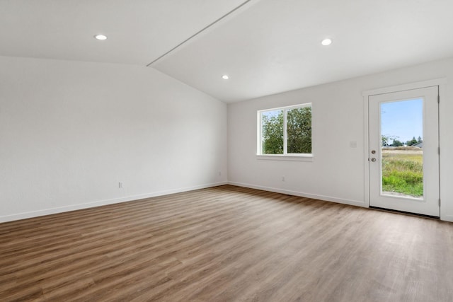 spare room featuring vaulted ceiling and hardwood / wood-style floors