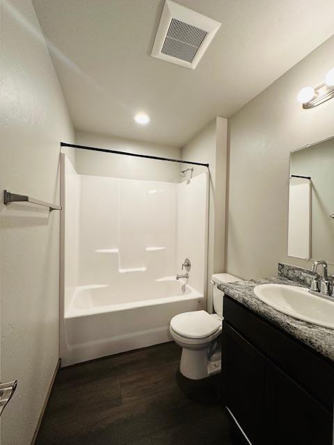 full bathroom with vanity, hardwood / wood-style flooring, bathtub / shower combination, and toilet