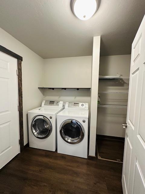 laundry room with dark hardwood / wood-style floors and washing machine and dryer