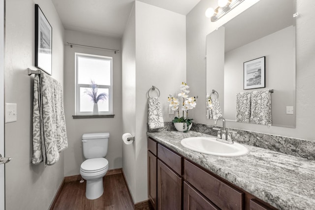 bathroom featuring wood finished floors, toilet, vanity, and baseboards