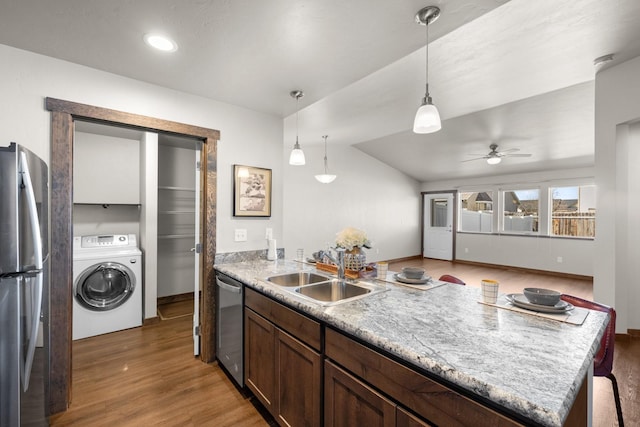 kitchen with washer / clothes dryer, stainless steel appliances, a sink, a peninsula, and light wood-style flooring