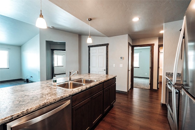 kitchen with vaulted ceiling, stainless steel appliances, decorative light fixtures, and sink