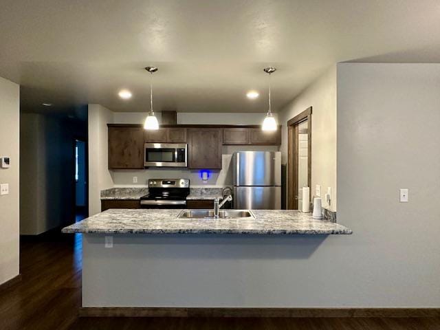 kitchen with hanging light fixtures, appliances with stainless steel finishes, sink, and dark brown cabinetry