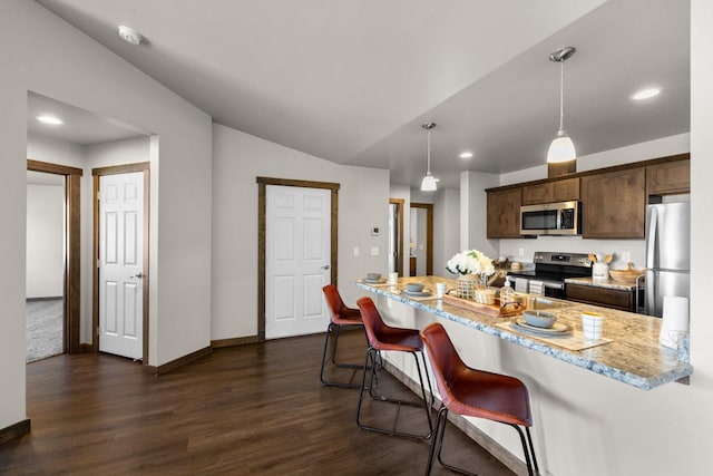 kitchen with stainless steel appliances, dark wood finished floors, dark brown cabinetry, a breakfast bar, and lofted ceiling
