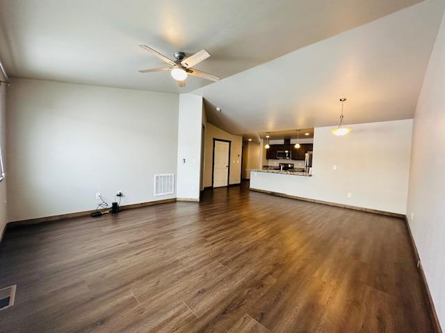 unfurnished living room featuring dark hardwood / wood-style flooring, lofted ceiling, and ceiling fan