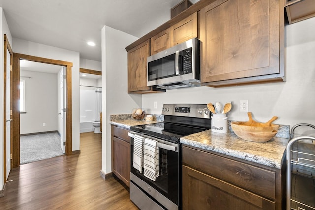 kitchen with stainless steel appliances, dark wood-style floors, light stone countertops, recessed lighting, and baseboards