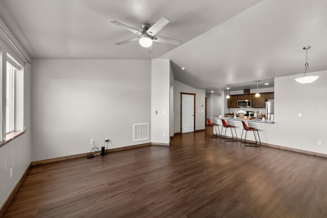 unfurnished living room featuring vaulted ceiling, dark wood finished floors, baseboards, and ceiling fan