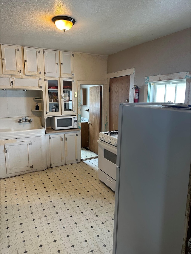 kitchen featuring white appliances, sink, and a textured ceiling