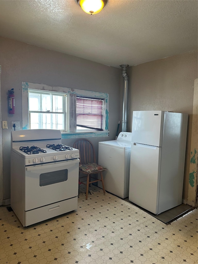 kitchen featuring white appliances, washer / dryer, and a textured ceiling