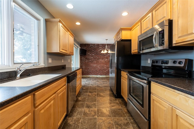 kitchen featuring stainless steel appliances, sink, decorative light fixtures, a notable chandelier, and brick wall