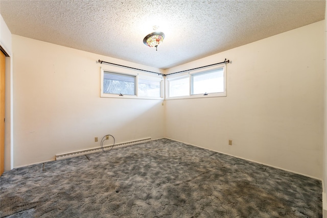 spare room featuring dark carpet, a textured ceiling, and a baseboard heating unit