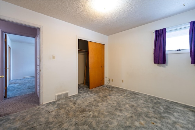 unfurnished bedroom featuring a textured ceiling, a closet, and dark colored carpet