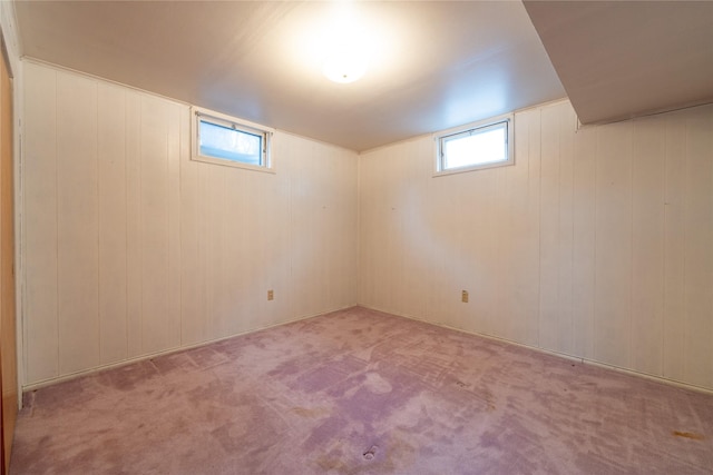 basement featuring light colored carpet and wooden walls