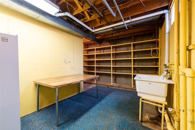 basement featuring sink, refrigerator, and carpet flooring