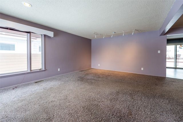 spare room featuring rail lighting, carpet flooring, and a textured ceiling