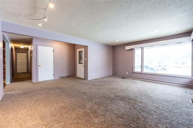 carpeted empty room featuring a textured ceiling