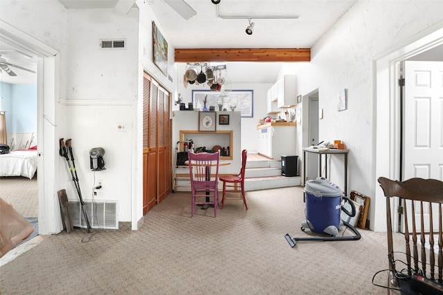 corridor with carpet floors, track lighting, and beam ceiling