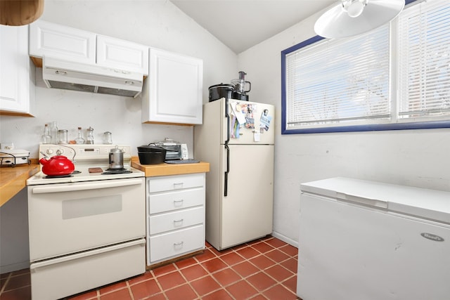 kitchen with white appliances, tile patterned flooring, vaulted ceiling, and white cabinets