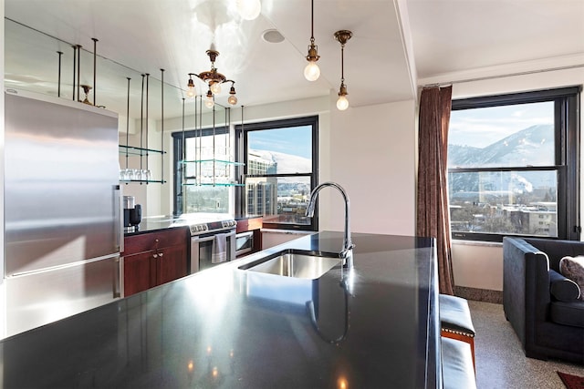 kitchen with appliances with stainless steel finishes, sink, hanging light fixtures, a notable chandelier, and a mountain view