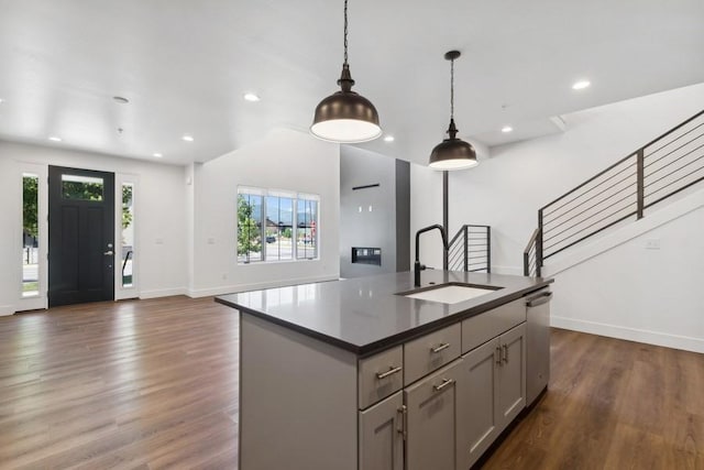 kitchen with sink, gray cabinetry, a center island with sink, dishwasher, and pendant lighting