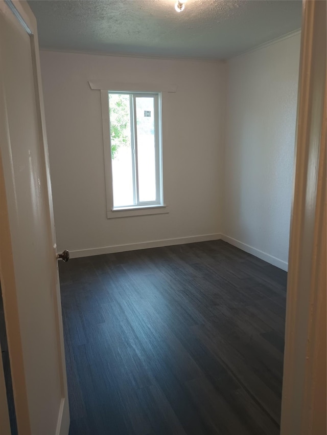 spare room with baseboards, a textured ceiling, and dark wood-type flooring