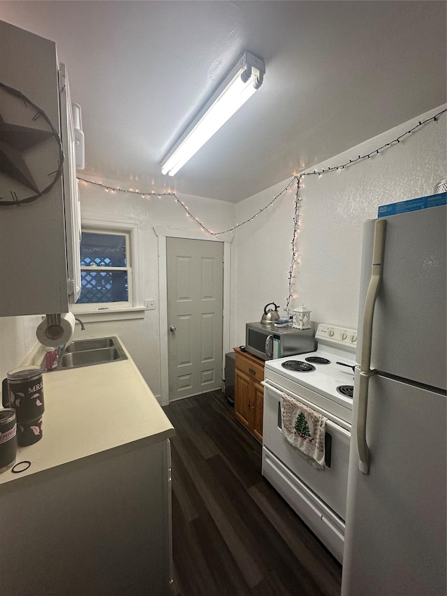 kitchen with white appliances, a sink, dark wood-style floors, and light countertops