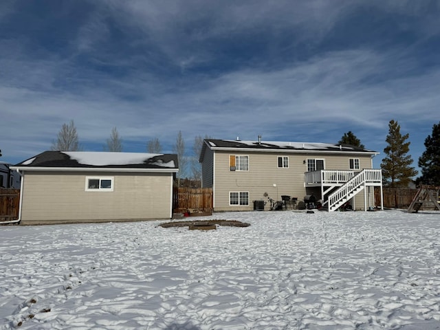 snow covered rear of property with a deck