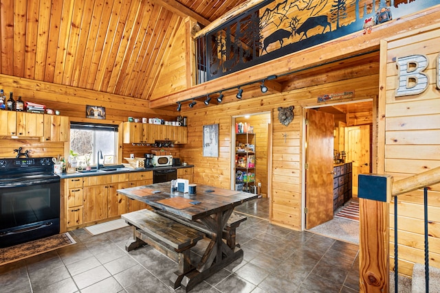 kitchen featuring sink, black appliances, dark tile patterned floors, and wood walls