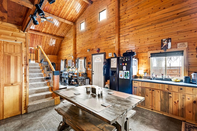 tiled dining space featuring wooden ceiling, beam ceiling, high vaulted ceiling, and wood walls