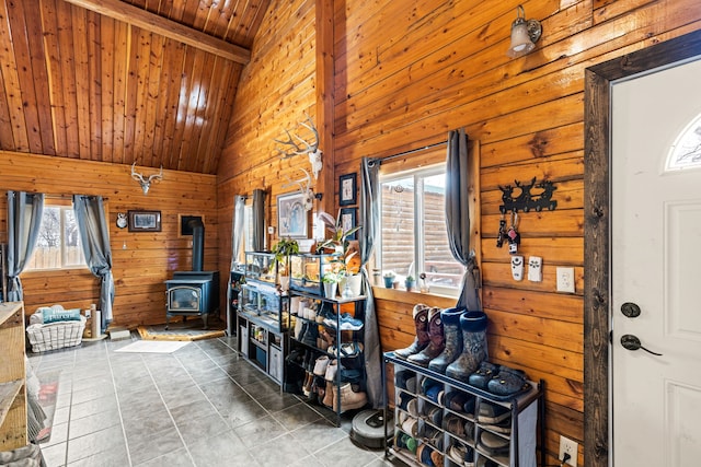 tiled entrance foyer featuring lofted ceiling with beams, a wood stove, wooden walls, and wood ceiling