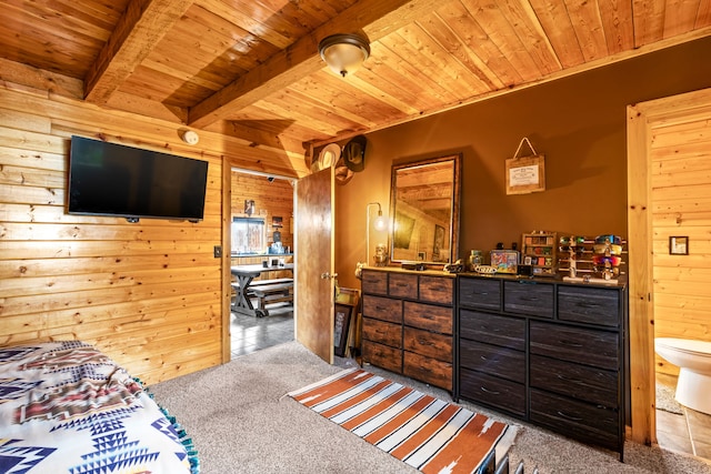 carpeted bedroom featuring wood ceiling, ensuite bathroom, wooden walls, and beam ceiling