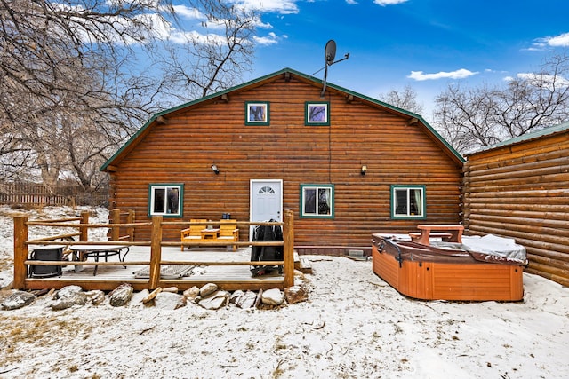 snow covered property with a wooden deck and a hot tub