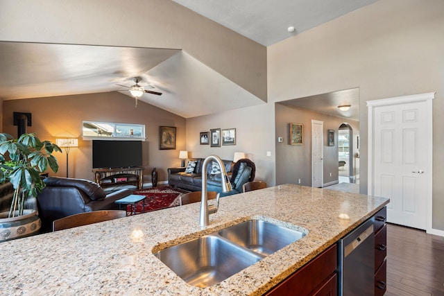 kitchen featuring lofted ceiling, sink, stainless steel dishwasher, light stone counters, and dark wood-type flooring