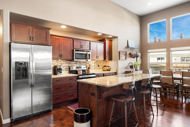 kitchen with sink, light stone countertops, dark hardwood / wood-style floors, and appliances with stainless steel finishes