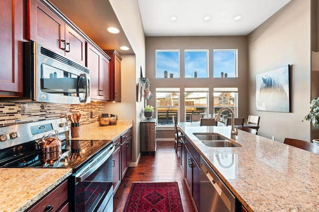 kitchen with a wealth of natural light, sink, decorative backsplash, stainless steel appliances, and light stone countertops