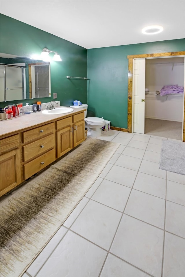 bathroom featuring tile patterned floors, vanity, toilet, and an enclosed shower