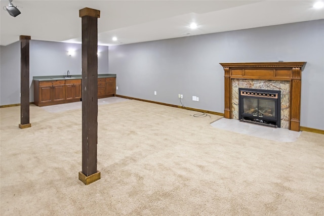 basement featuring a premium fireplace, indoor bar, and light colored carpet