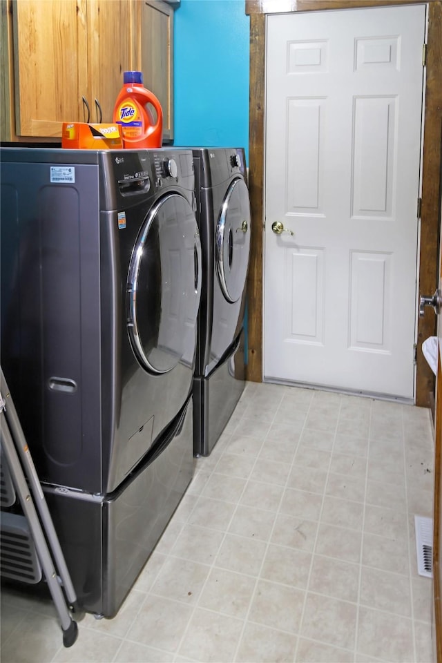 clothes washing area with cabinets, light tile patterned flooring, and independent washer and dryer