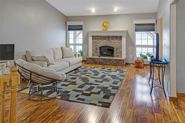 living room with hardwood / wood-style flooring, a brick fireplace, and a healthy amount of sunlight