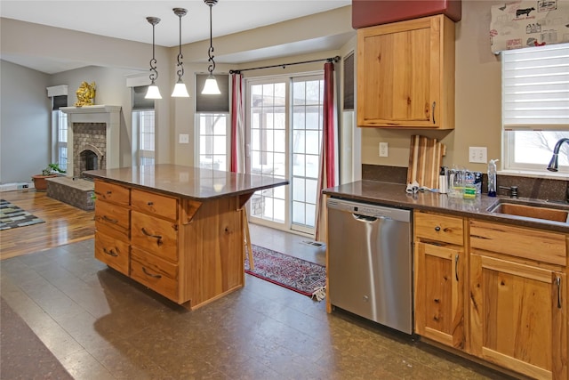 kitchen featuring hanging light fixtures, sink, stainless steel dishwasher, and a fireplace