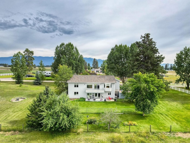 back of property with a yard, a mountain view, and a rural view