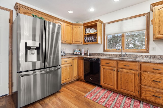 kitchen with sink, stainless steel fridge with ice dispenser, black dishwasher, light stone countertops, and light hardwood / wood-style floors