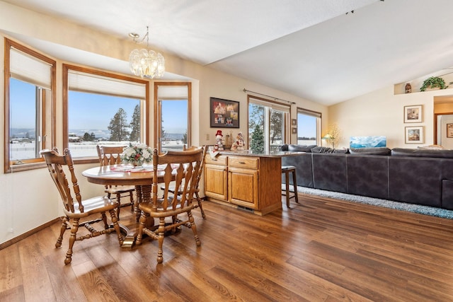 dining room featuring dark wood-type flooring, lofted ceiling, and a chandelier