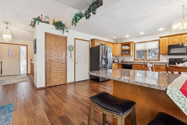 kitchen with a kitchen breakfast bar, dark hardwood / wood-style flooring, hanging light fixtures, and black appliances