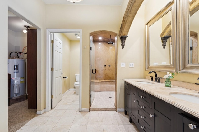 bathroom featuring water heater, vanity, a shower with shower door, tile patterned floors, and toilet