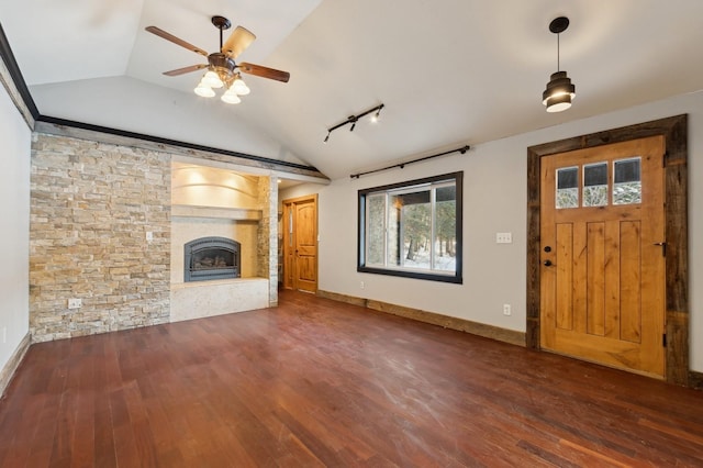 unfurnished living room featuring track lighting, dark hardwood / wood-style floors, vaulted ceiling, and a fireplace