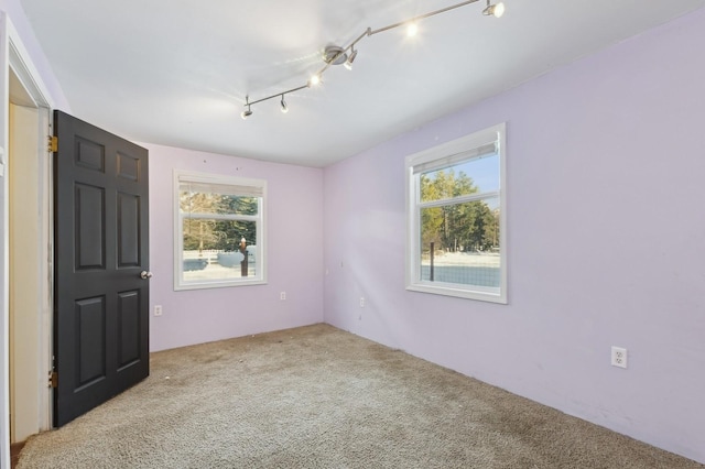 unfurnished room featuring light colored carpet and rail lighting