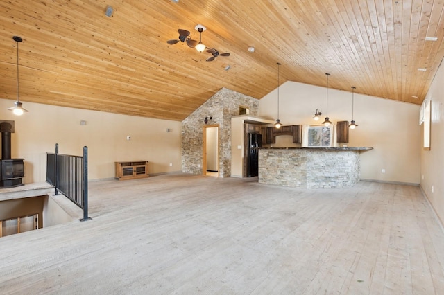 unfurnished living room featuring light hardwood / wood-style flooring, wooden ceiling, ceiling fan, and a wood stove